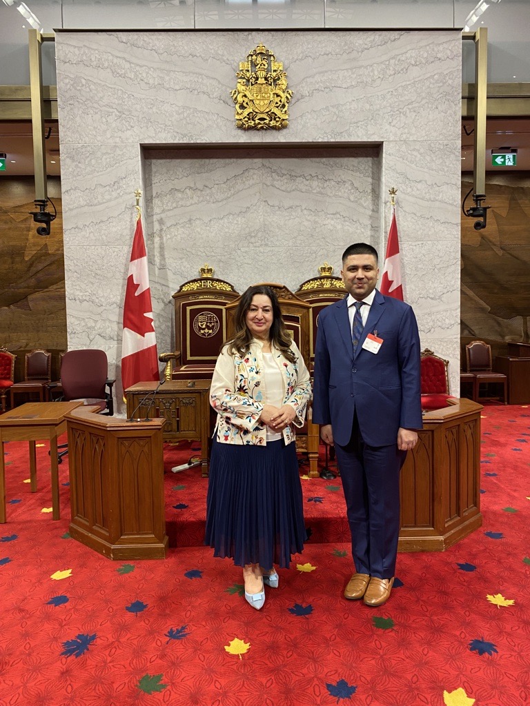 Blavatnik School alumnus Shoaib Rizvi stands next to the Canadian Senator Salma Ataullahjan with a background of the Canadian flags